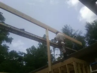 Carpenter setting a ridge beam over a new addition frame — Ice Dam Removal by Roofing Brothers in Stanton